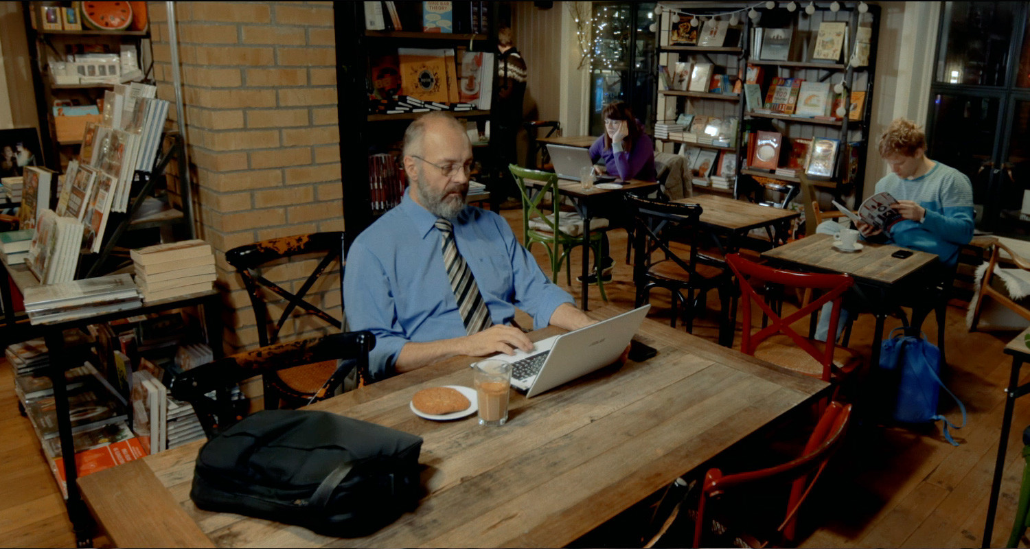 Man on computer in cafe using free wifi. This is a vacation and cybersecurity risk.