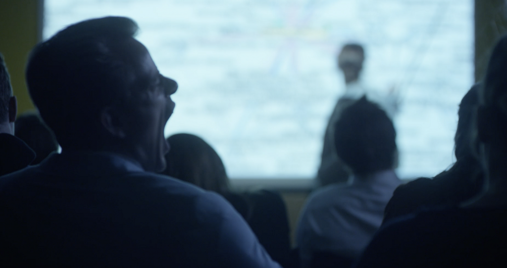 Man yawning at a lecture. This is why companies offer online cyber security awareness training for employees.