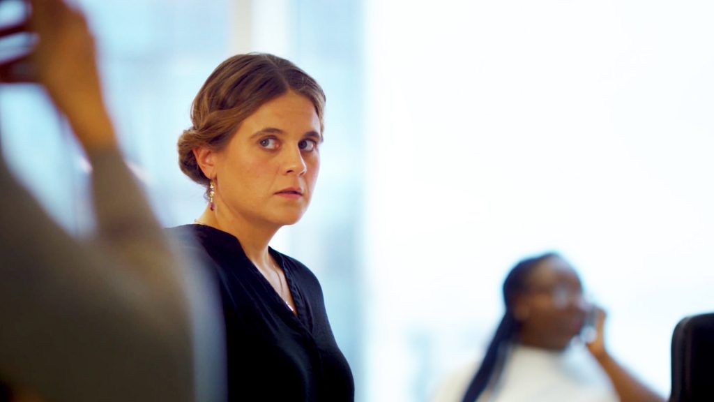 New cybersecurity training video about insider threat. A woman looks suspicious of coworker's behavior.