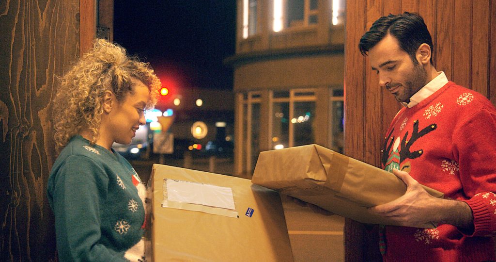 Woman and man stand by their open front door in Reykjavik, having received identical deliveries in brown wrapping. Still from video about delivery phishing scams.